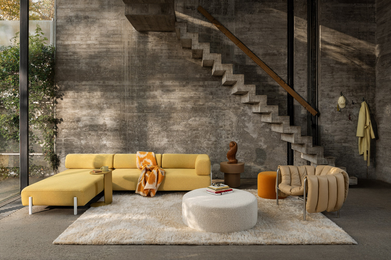 A living room scene featuring Palo Modular Corner Sofa Left Sunflower, Lolly Side Table Ochre Yellow, Monster Throw Ochre / Off-White Ring, Bon Pouf Round Large Eggshell, Stump Side Table Natural, Monster Rug Beige / Off-White, Puffy Lounge Chair Sand