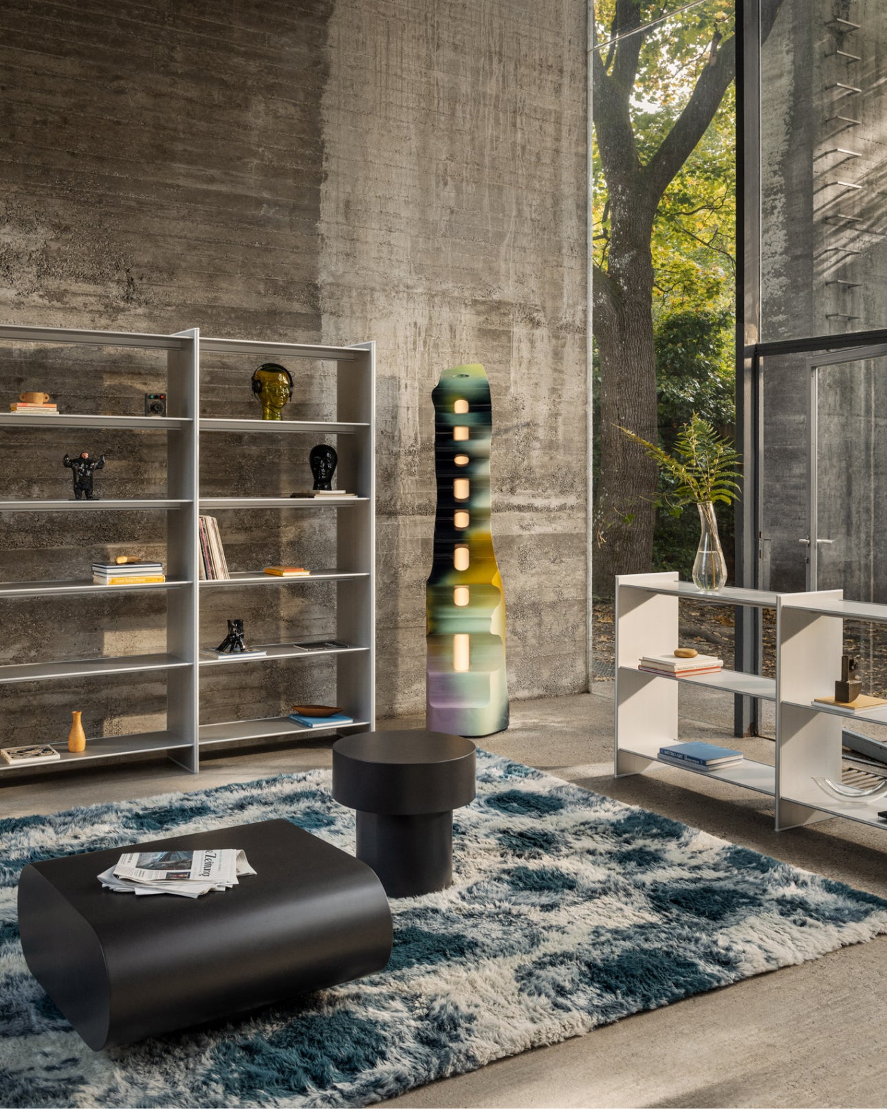 A living room / lounge scene featuring 2 T Shelf configurations, Monster Rug in Dark Teal / Off-White, and Stump Coffee and Side Tables.