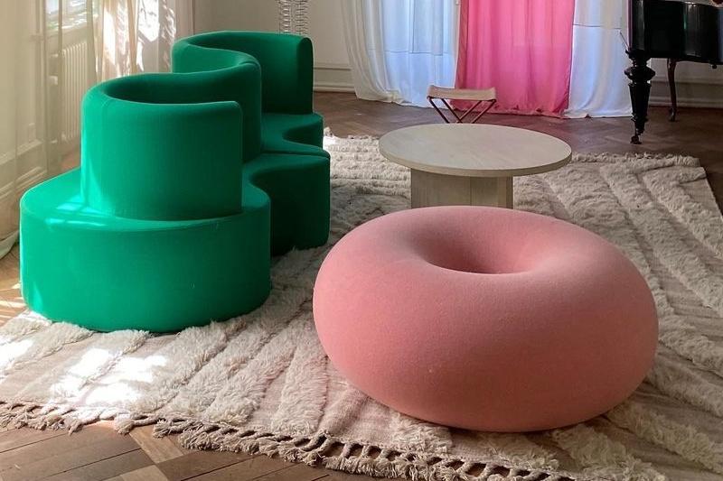 User generated content of the Boa Pouf in Cotton Candy on a rug next to a green abstract sofa.