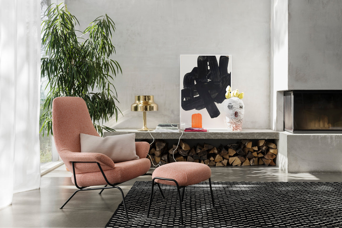 A living room scene featuring a Hai Lounge Chair + Ottoman in Melange Coral and a Rain Rug.