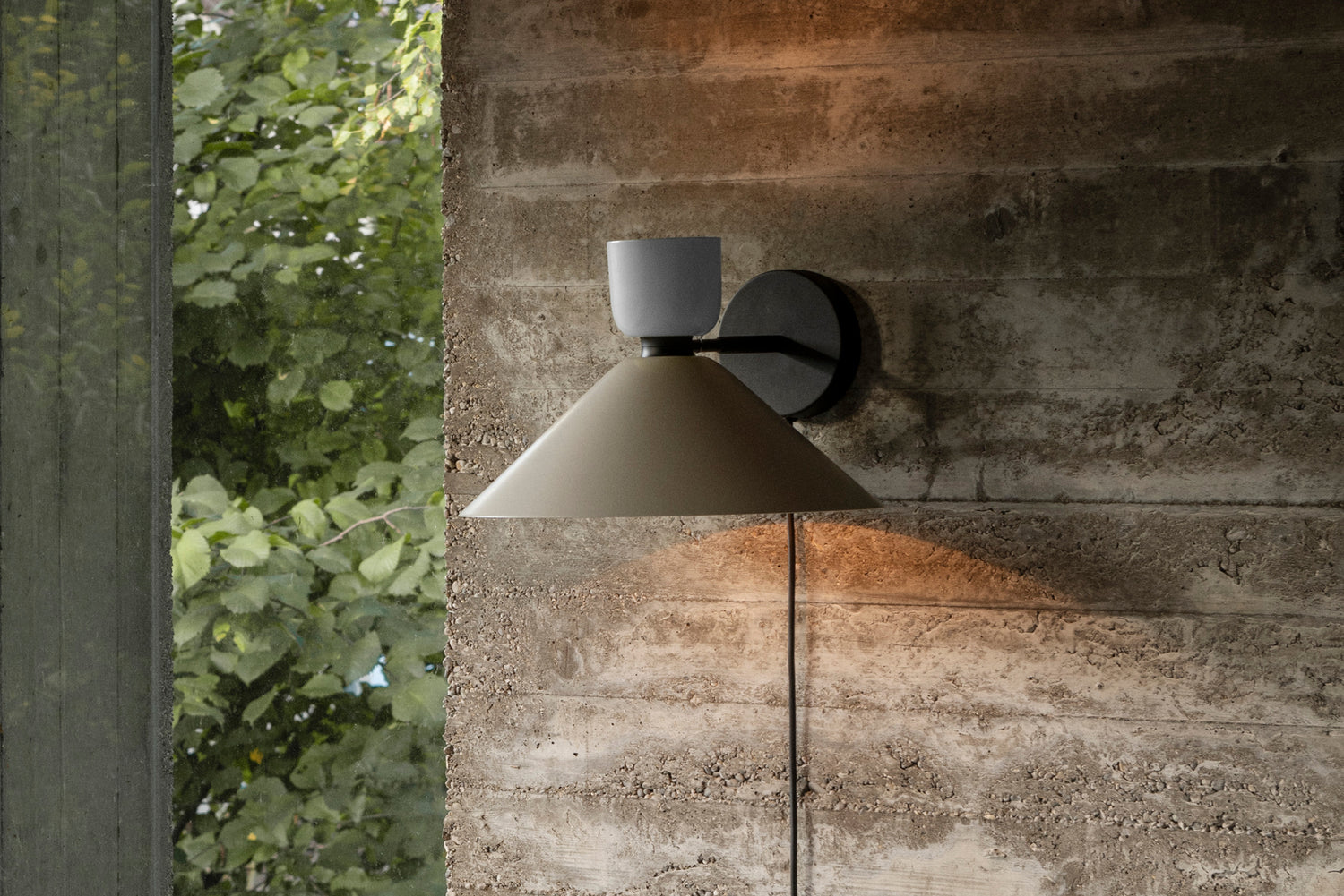An Alphabeta Wall Light + Cable mounted onto a stone wall.