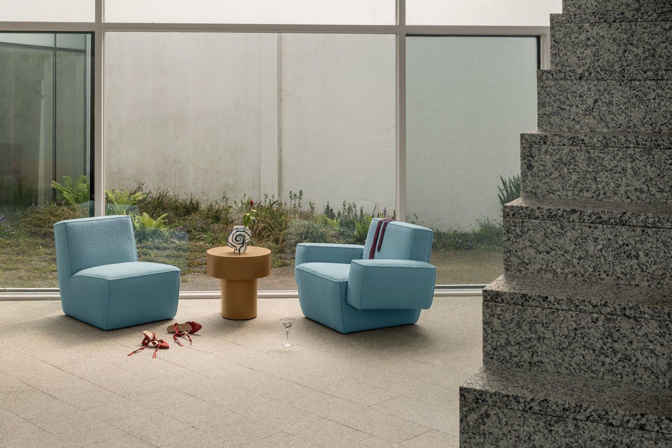 A lifestyle image of a lounge scene featuring Hunk Lounge Chair, Hunk Lounge Chair with Armrests, and Stump Side Tables.