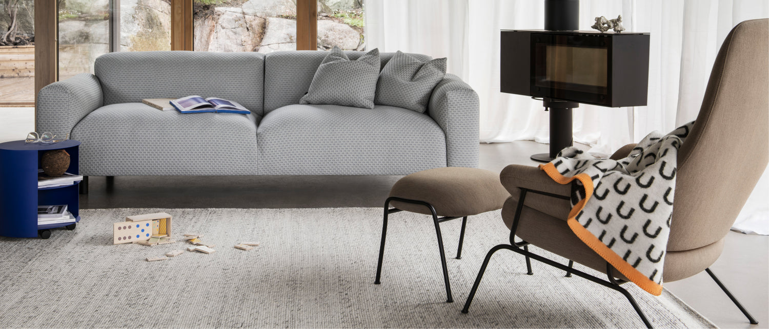 Hem - A living room scene featuring Hide Side Table, Dune Rug Large, Koti 3-Seater Sofa, Hai Lounge Chair + Ottoman, and Arch Throw.