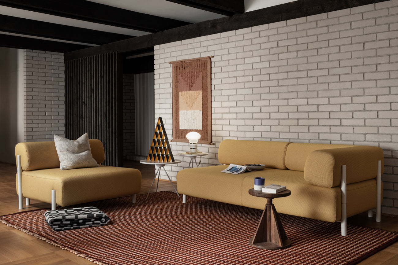 A living room scene featuring Rope Rug Large Teracotta, Palo Sofas, All Wood Stool Rocket Walnut, Vienna Throw, Key Side and Coffee Table Set White, and the Incredible House of Cards limited edition decorative object.