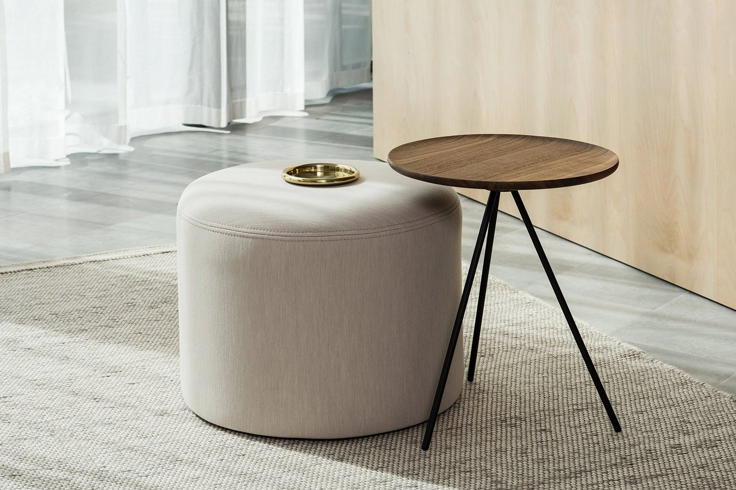 A Bon Pouf Round in Shell stands next to a Key Side Table in Walnut.